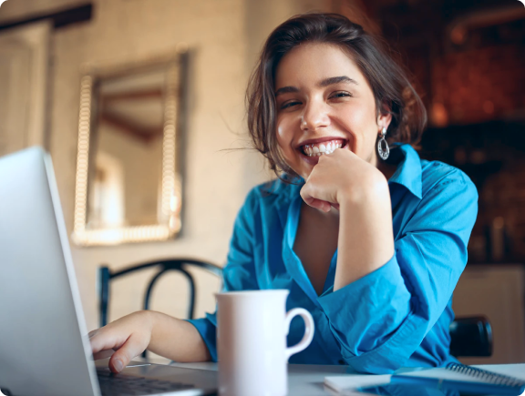 Mulher sorrindo usando um laptop.
